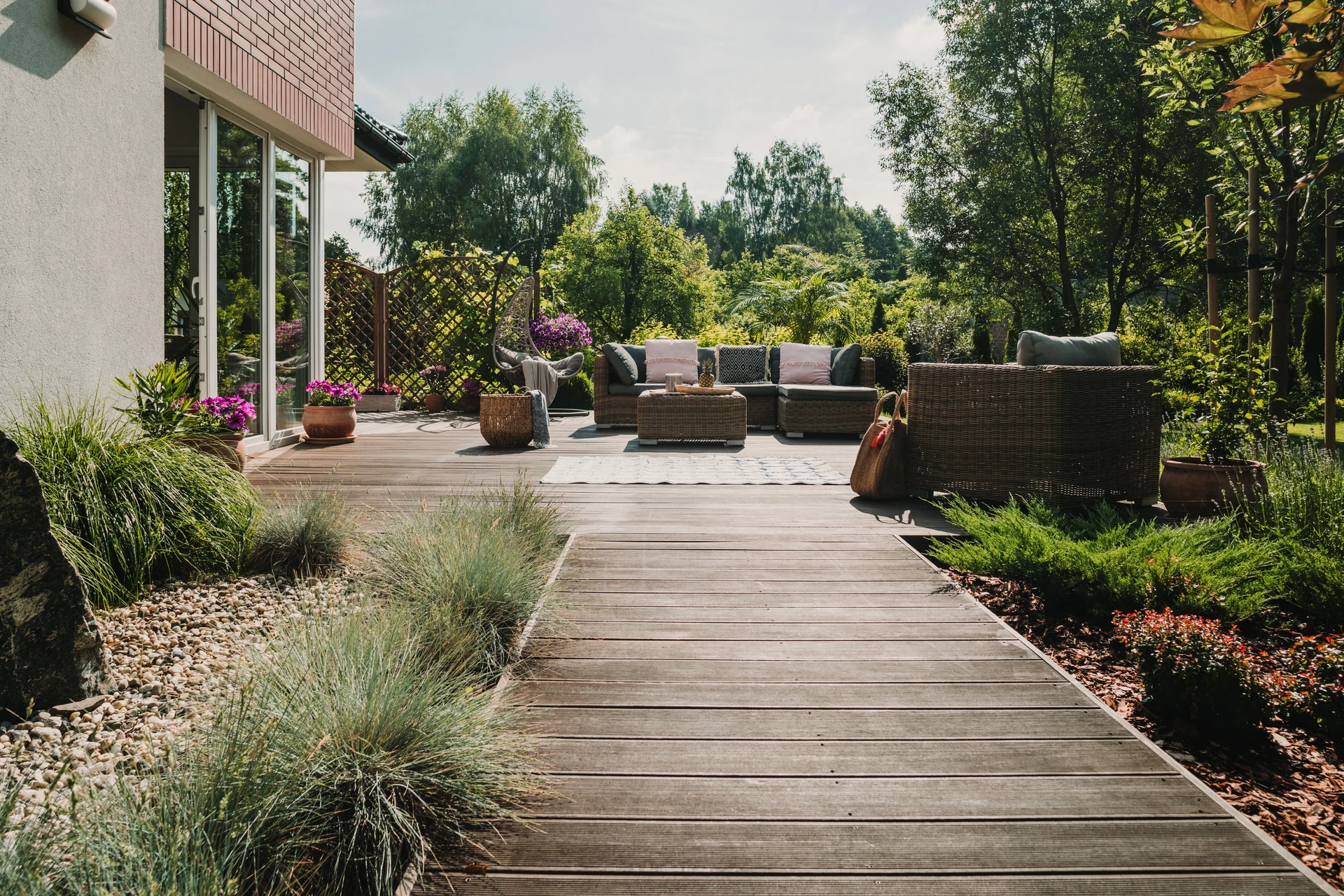 Terrasse extérieure moderne avec salon de jardin en résine tressée, coussins beiges et gris