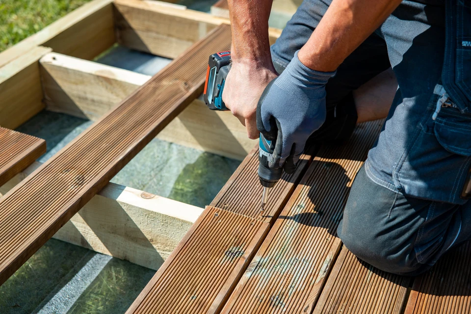 Chantier extérieur de construction d'une terrasse en bois dans jardin résidentiel clôturé